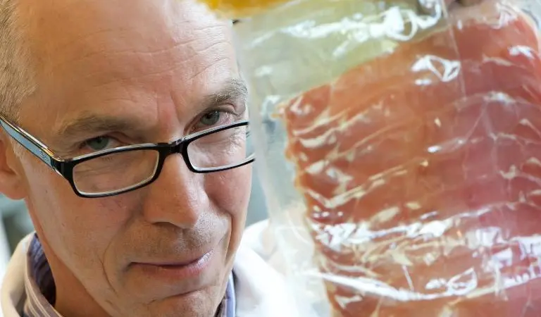 Professor Andrew Mills with food packaging incorporating the intelligent plastic indicator.  The yellow part is the indicator and it has changed colour to show that the food it contains has spoiled.