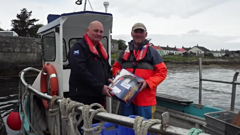 Dougie Brown, right, receiving his new free PFD from Iain MacEachan of Marine Scotland onboard his replacement boat