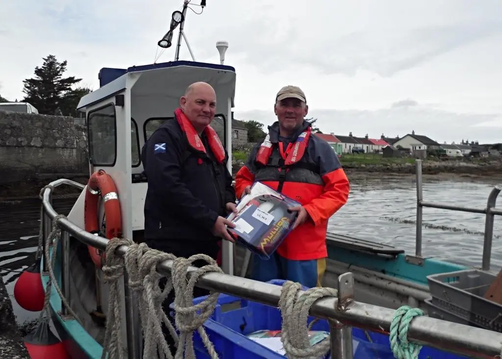 Dougie Brown, right, receiving his new free PFD from Iain MacEachan of Marine Scotland onboard his replacement boat
