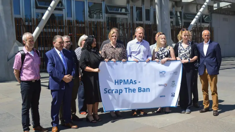 Members of fishing organisations holding a 'HPMA - Scrap The Ban' poster