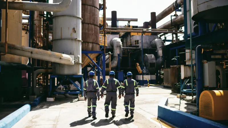 Three workers outside at a fish oil and fishmeal factory