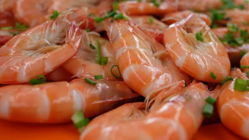 The image shows cooked fresh prawns on a plate seasoned with parsley