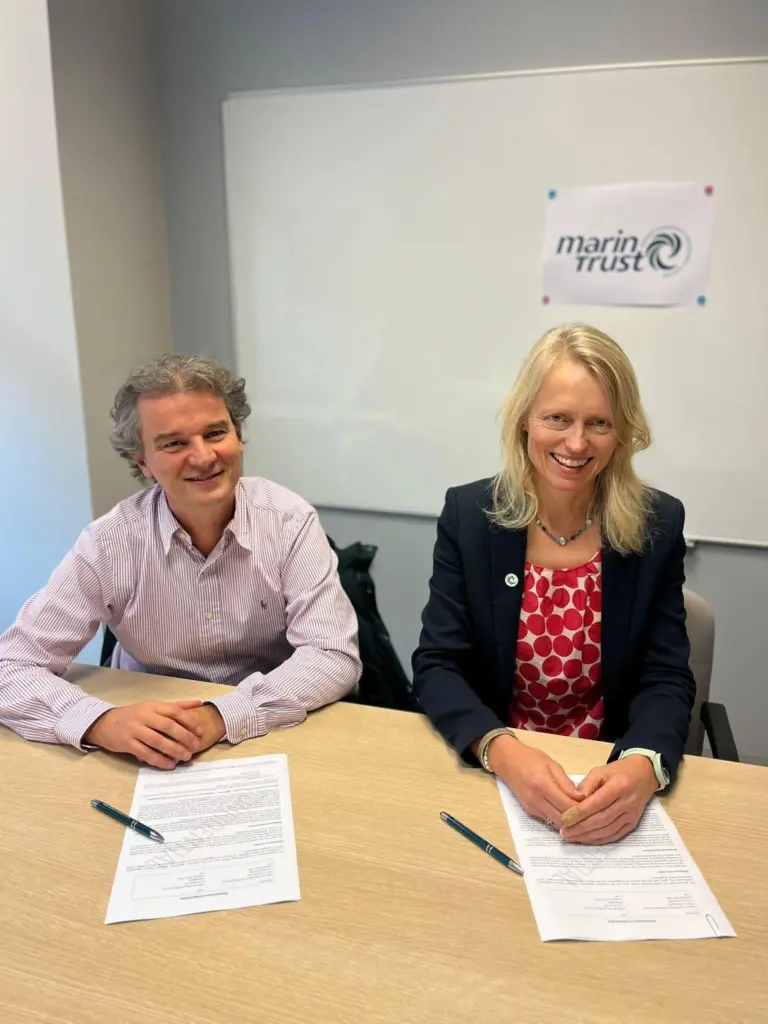 Nicolas Guichoux, chief programme officer at MSC, and Libby Woodhatch, executive chair at MarinTrust sitting at a desk during an MoU signing