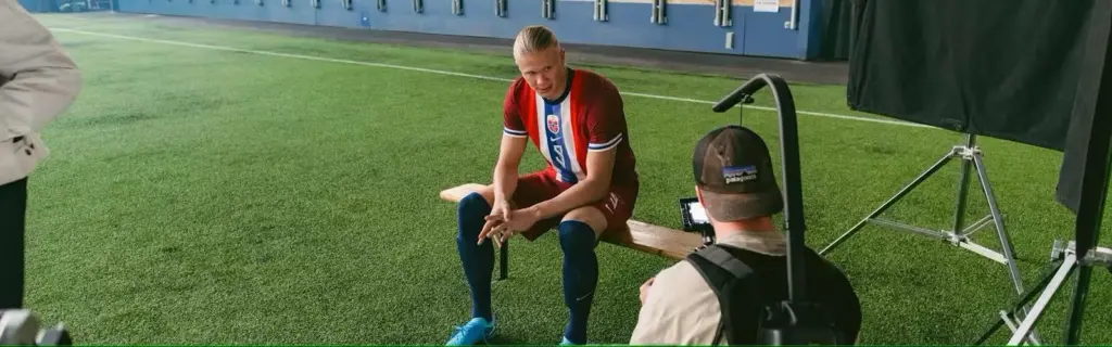 Erling Haaland sitting on a bench at a football stadium being filmed for an ad campaign by the Norwegian Seafood Council