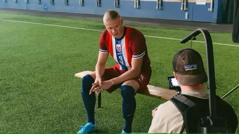 Erling Haaland sitting on a bench at a football stadium being filmed for an ad campaign by the Norwegian Seafood Council