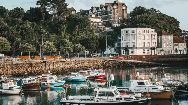 The image shows boats moored near to the shore at Folkstone Harbour
