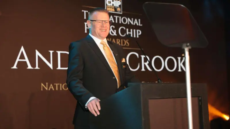 Andrew Crook, president of the National Federation of Fish Friers standing at a podium at the National Fish & Chip Awards 2024