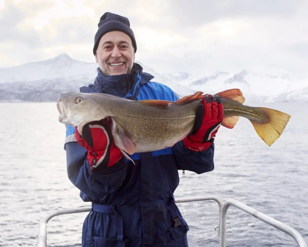 Chef Michel Roux holding a fish and looking mightily pleased