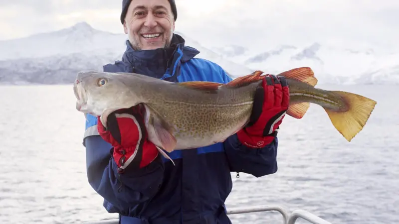 Chef Michel Roux holding a fish and looking mightily pleased
