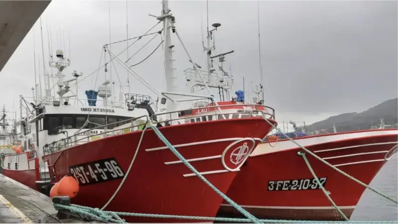 Two red and white fishing vessels at port