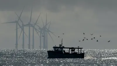 Image of a fishing boat with offshore wind turbines in the background
