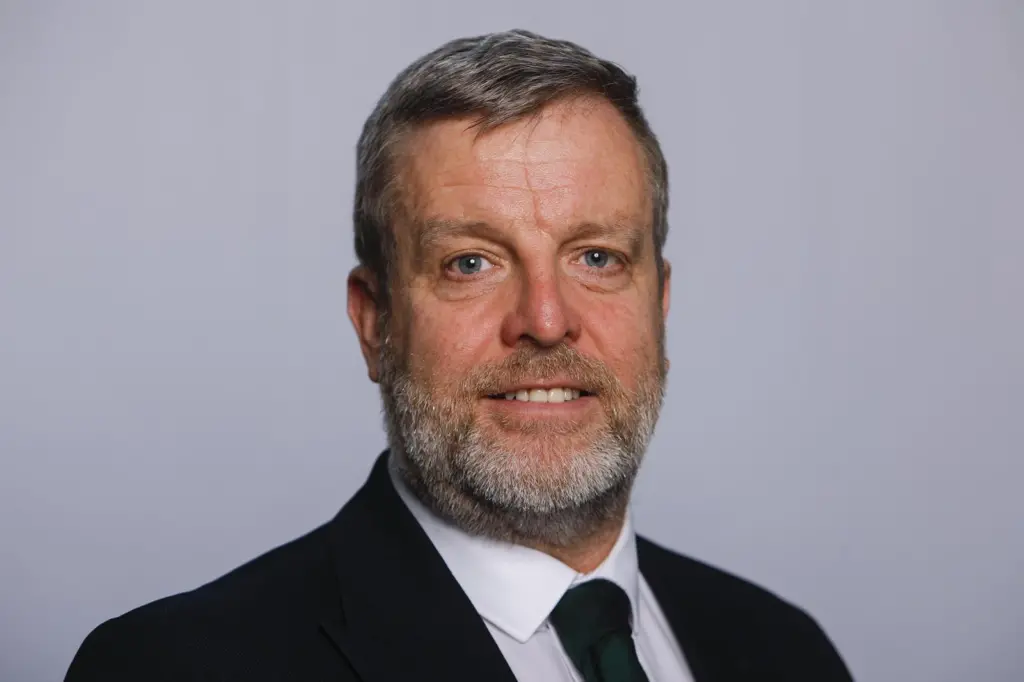 The image shows a headshot of Finlay Carson MSP in a black suit and tie